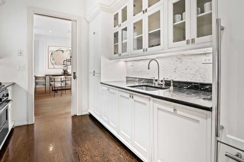 White kitchen with black marble counters at 1 Central Park South 701, Central Park South — photo 3 of 7