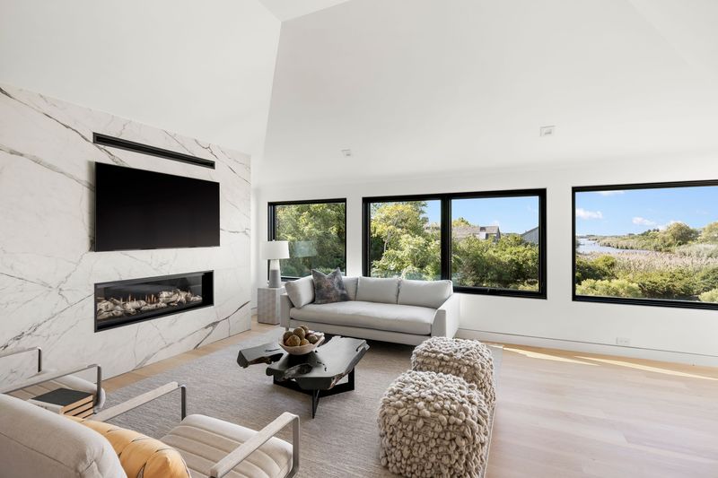 Living room fireplace bay views at 1076 Ocean Road, Bridgehampton — photo 6 of 11