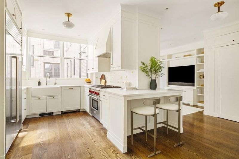 Windowed eat-in kitchen with a Wolf range and island seating at 1155 Park Avenue 10SW, Carnegie Hill — photo 4 of 12