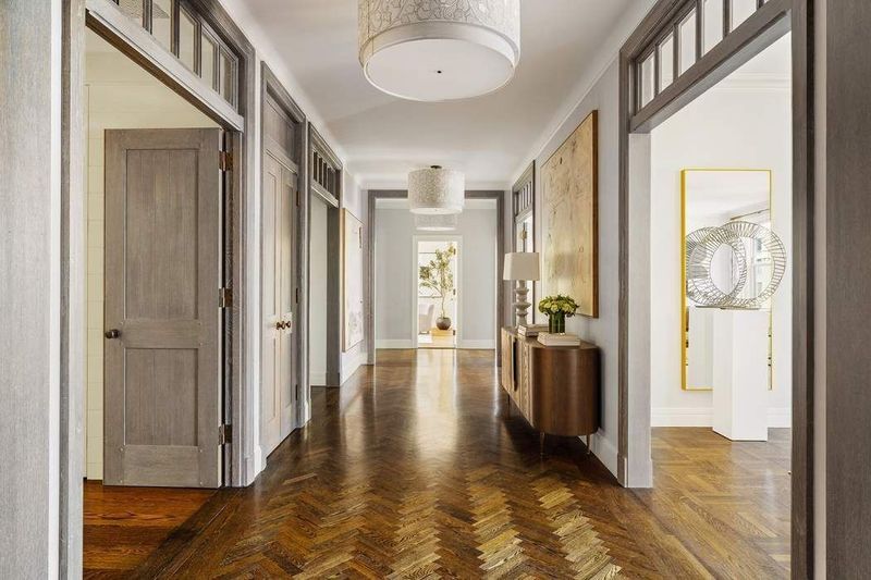 Long hallway with herringbone floors and pocket-door openings at 1155 Park Avenue 10SW, Carnegie Hill — photo 10 of 12