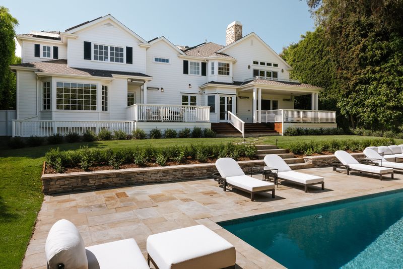 Pool, lounge terrace and the white Traditional facade behind privacy hedges at 1228 Amalfi Drive, Pacific Palisades