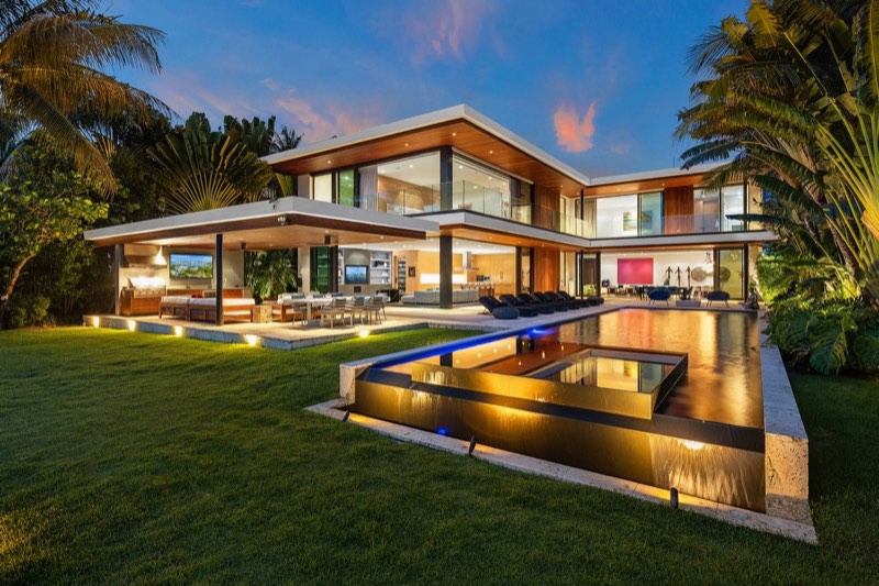 Twilight exterior with pool and lawn at 126 West San Marino Drive on San Marino Island, Miami Beach