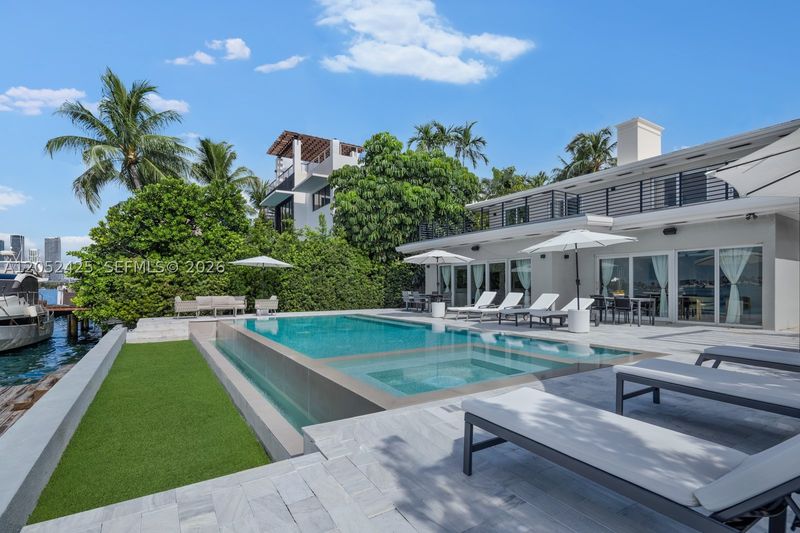 The rear of the home, with the pool and lawn at 1300 South Venetian Way, San Marco Island — photo 8 of 10