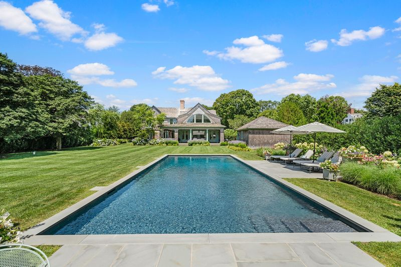 Heated gunite pool and lawn with the pool house beyond at 134 Herrick Road, Southampton Village