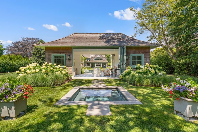 Pool house and spa framed by hydrangea and perennial gardens at 134 Herrick Road, Southampton Village — photo 2 of 12