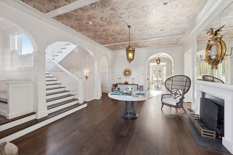 Grand entry hall with a staircase and arched openings at 134 Herrick Road, Southampton Village — photo 6 of 12