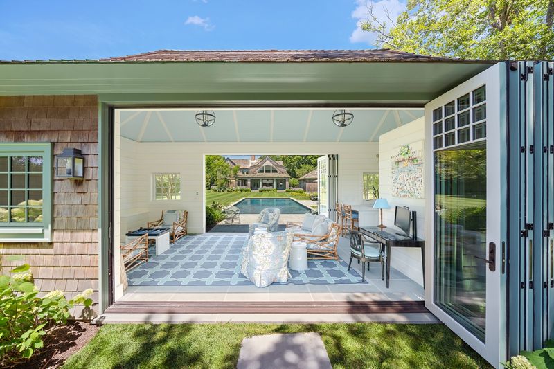 Climate-controlled pool house with accordion doors open to the terrace at 134 Herrick Road, Southampton Village — photo 9 of 12