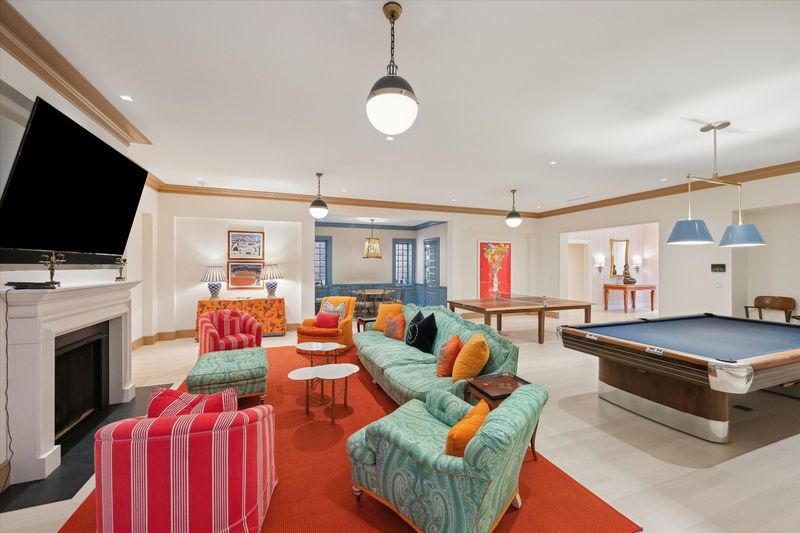 Lower-level living and play area with a fireplace and billiards table at 134 Herrick Road, Southampton Village — photo 10 of 12