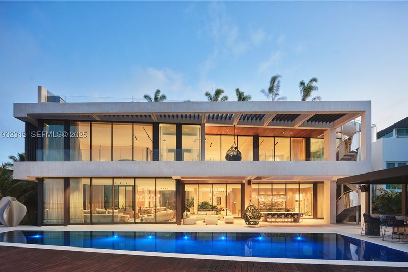 The waterfront facade at dusk, with walls of glass above the pool at 1413 North Venetian Way, San Marco Island