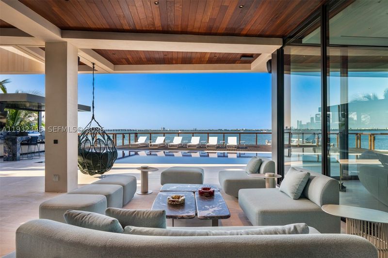 The covered waterfront terrace, opening to the pool and bay at 1413 North Venetian Way, San Marco Island — photo 4 of 9