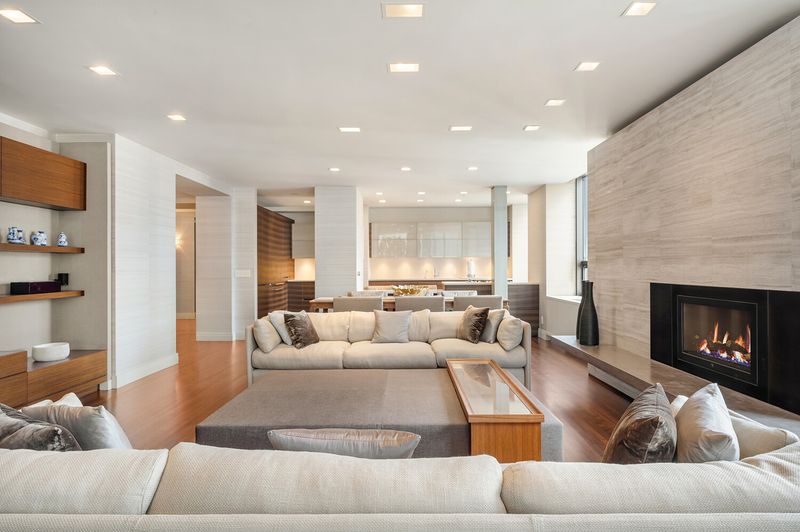 Long view of the living room toward the open kitchen and fireplace wall at 15 West 53rd Street #29BC, Midtown Manhattan — photo 2 of 12