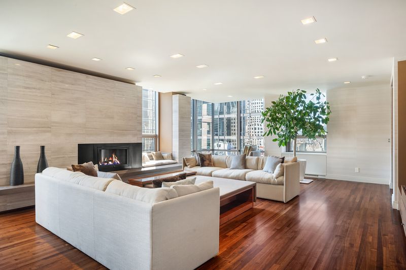 Living room with the Venetian plaster fireplace wall and south/east windows at 15 West 53rd Street #29BC, Midtown Manhattan — photo 3 of 12