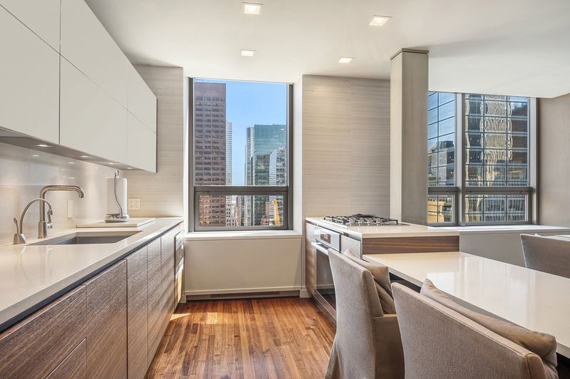 Open kitchen with walnut cabinetry and window views at 15 West 53rd Street #29BC, Midtown Manhattan — photo 6 of 12