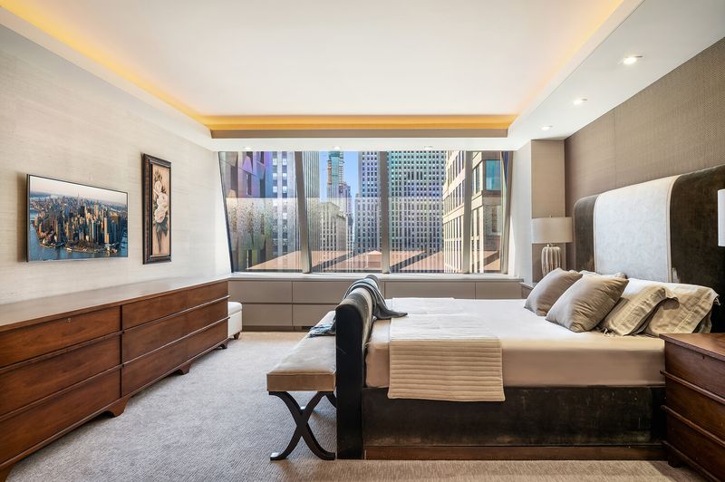 Primary bedroom with cove lighting and city view at 15 West 53rd Street #29BC, Midtown Manhattan — photo 7 of 12