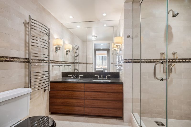 Primary bath, travertine and walnut double vanity at 15 West 53rd Street #29BC, Midtown Manhattan — photo 9 of 12