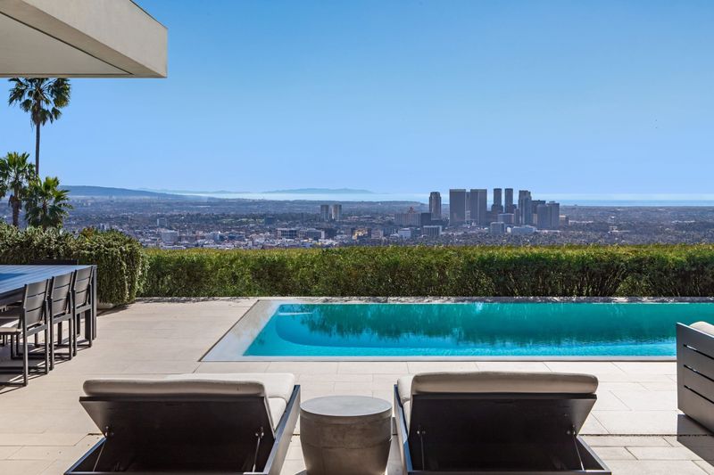 Poolside loungers facing the city skyline at 1535 Carla Ridge, Trousdale Estates — photo 4 of 10