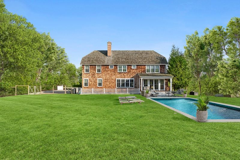 The shingled house and heated gunite pool across the back lawn at 162 Norris Lane, Bridgehampton