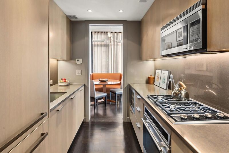 Galley kitchen with light-wood cabinetry opening to the dining banquette at 170 East End Avenue 3J, Upper East Side — photo 3 of 9