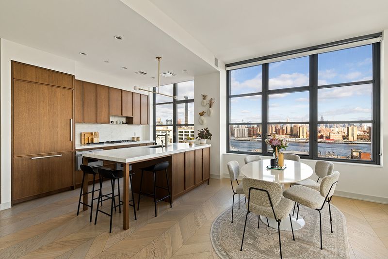 Kitchen island and dining area overlooking the East River at 180 Front Street 11E, DUMBO — photo 2 of 9