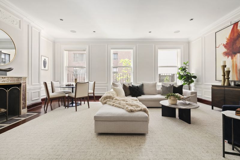 The full-width living room, with a fireplace and a row of tall windows at 2 East 80th Street #7, Upper East Side — photo 2 of 8