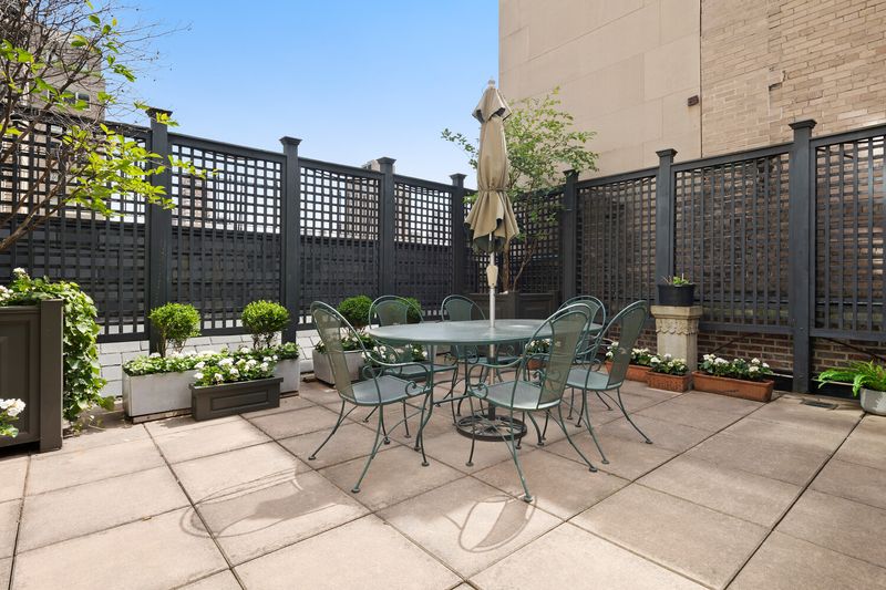 The landscaped terrace, with dining and lounge seating behind trellised screens at 2 East 80th Street #7, Upper East Side — photo 3 of 8