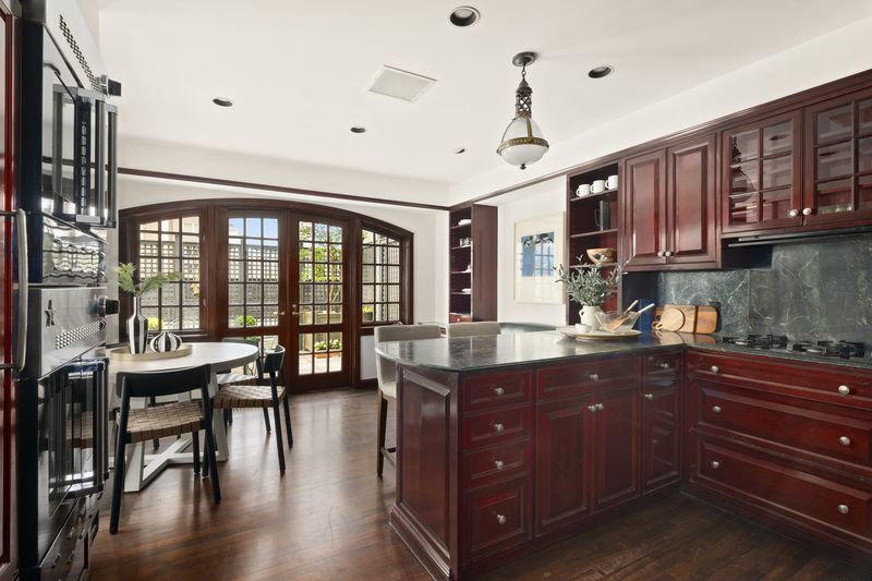 The eat-in kitchen, with wood cabinetry and French doors to the terrace at 2 East 80th Street #7, Upper East Side — photo 4 of 8
