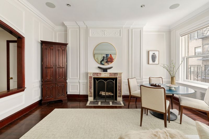 A sitting room with a marble fireplace and paneled walls at 2 East 80th Street #7, Upper East Side — photo 5 of 8