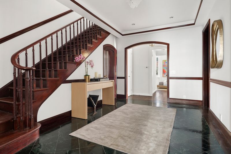The staircase and a gallery hall with arched doorways at 2 East 80th Street #7, Upper East Side — photo 6 of 8