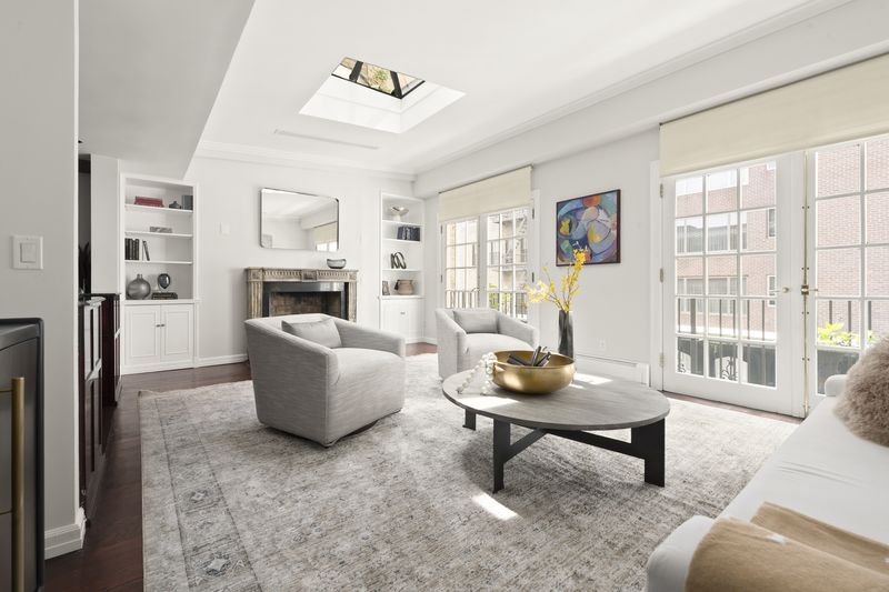 A living room with a fireplace under a skylight at 2 East 80th Street #7, Upper East Side — photo 7 of 8