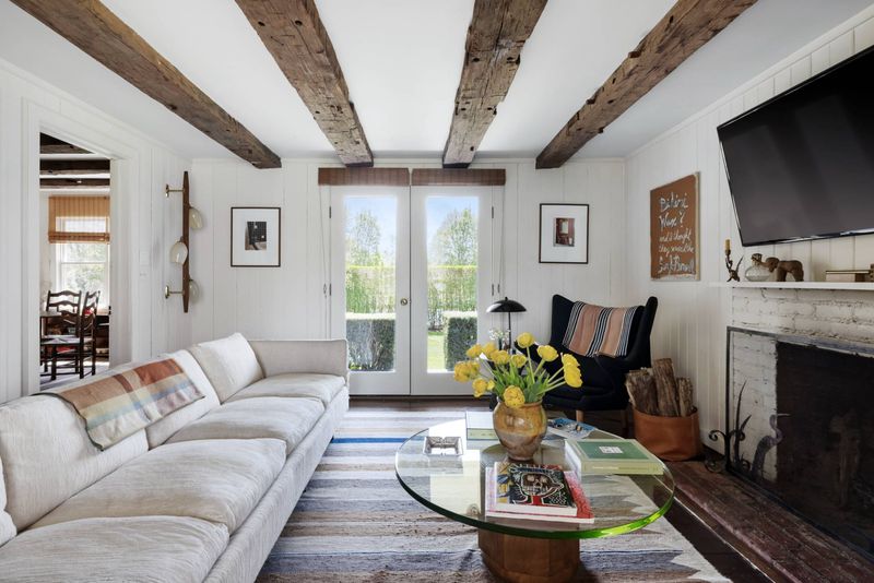 Living room with beamed ceiling and fireplace at 216 Sagaponack Road, Bridgehampton — photo 3 of 12