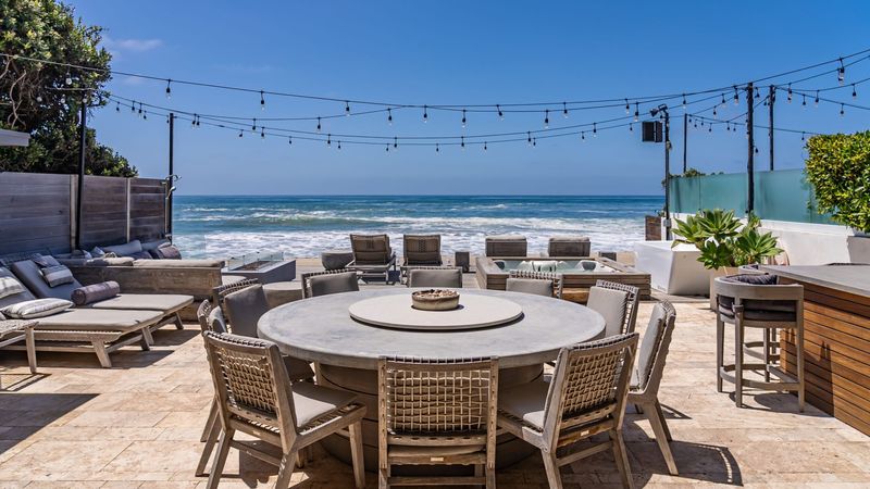 Beachfront deck with round dining table and ocean view at 23812 Malibu Road, Malibu — photo 2 of 8