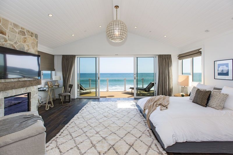 Primary bedroom with stone fireplace and ocean terrace at 23812 Malibu Road, Malibu — photo 8 of 8
