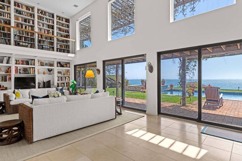 Living room opening through sliding glass doors to the pool terrace at 24 Aqua Drive, Southampton — photo 6 of 11
