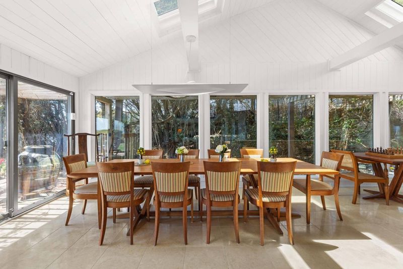 Dining area under a vaulted, skylit ceiling with water views at 24 Aqua Drive, Southampton — photo 7 of 11