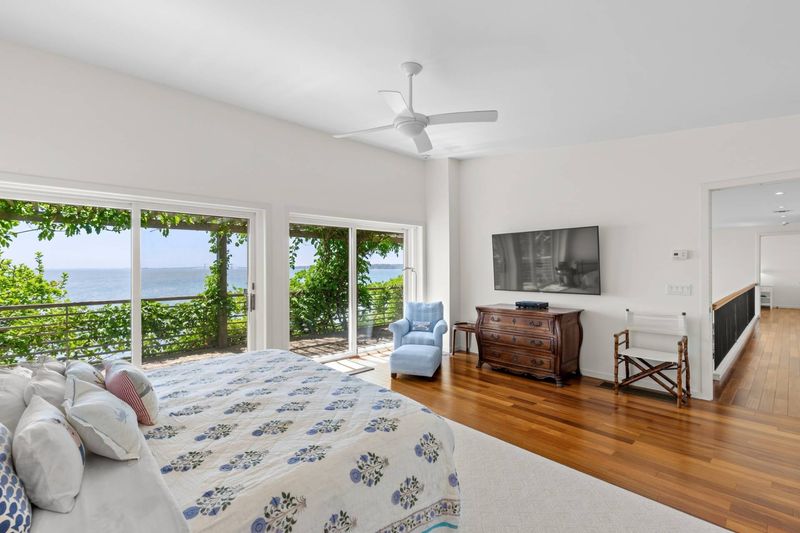 Bedroom with sliding glass doors and water views at 24 Aqua Drive, Southampton — photo 9 of 11
