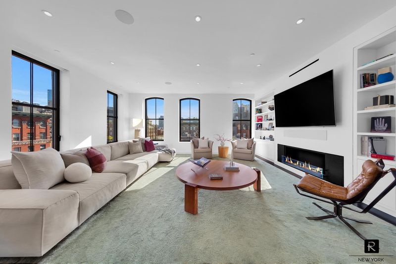 Living room with linear fireplace, built-ins and arched Tribeca windows at 250 West Street 9JK, Tribeca