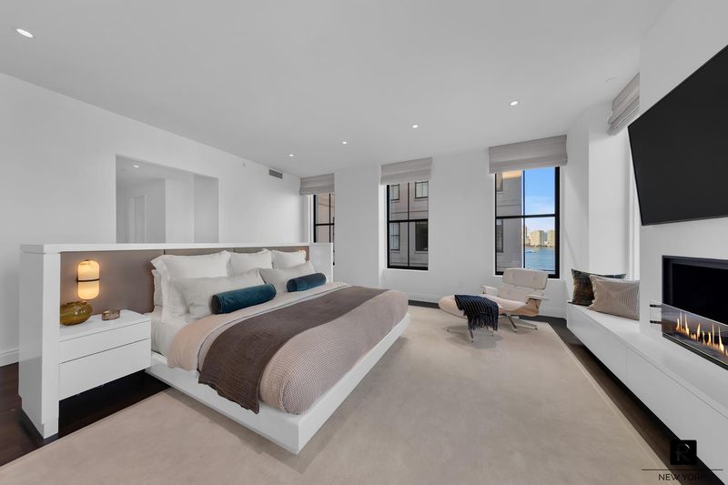 Corner primary bedroom with gas fireplace at 250 West Street 9JK, Tribeca — photo 6 of 12