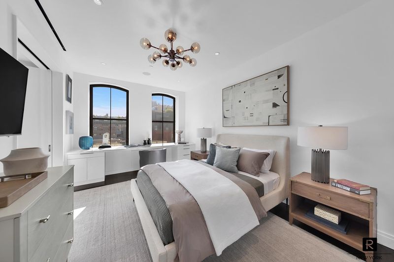 Secondary bedroom with built-in desk and arched windows at 250 West Street 9JK, Tribeca — photo 8 of 12