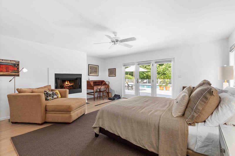 Guest bedroom with fireplace and pool doors at 3 Acorn Path, Quogue — photo 9 of 9