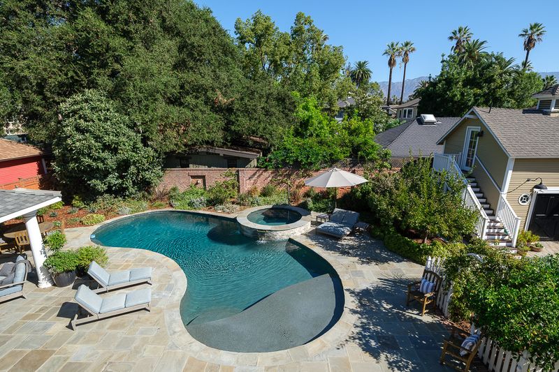 An aerial view of the rear garden, with a free-form pool and spa, the cabana and mountain views beyond at 303 Markham Place, Pasadena — photo 5 of 12
