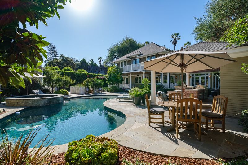 The pool terrace, with an umbrella-shaded dining table beside the water at 303 Markham Place, Pasadena — photo 6 of 12