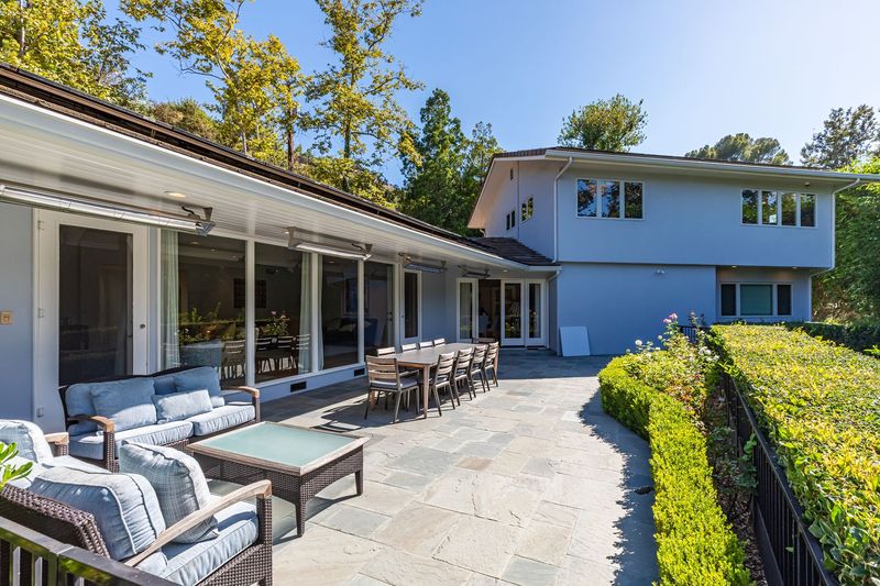 A covered terrace with lounge seating and outdoor dining runs the length of the house at 3101 Fryman Road, Studio City — photo 3 of 12