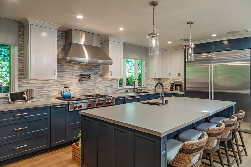 The kitchen, with a large island with counter seating, a professional-style range and a stainless refrigerator at 3101 Fryman Road, Studio City — photo 5 of 12