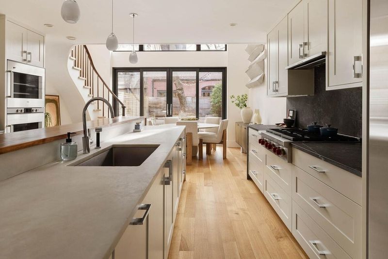 Garden-level kitchen with stone island and double-height glass wall at 53 West 71st Street, Upper West Side