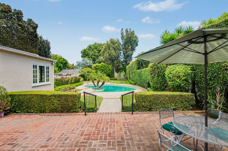 Patio dining under an umbrella beside the pool at 608 Trenton Drive, Beverly Hills Flats — photo 3 of 10