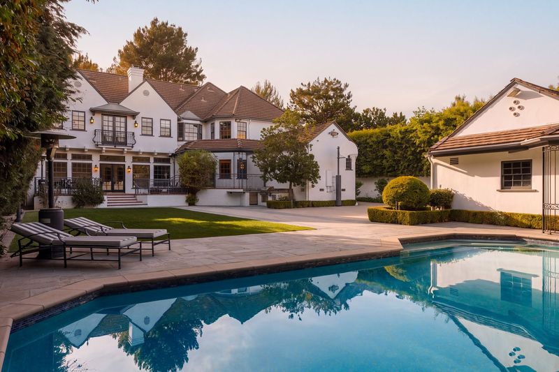 The pool and the rear facade, with lounge chairs on the brick terrace at 628 North Sierra Drive, Beverly Hills — photo 2 of 8