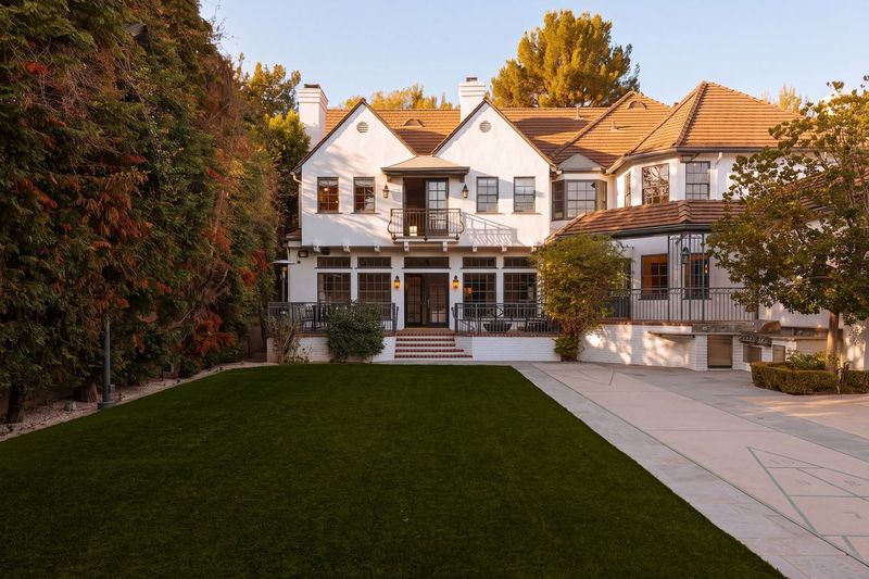 The rear lawn, framed by tall hedges, with the house beyond at 628 North Sierra Drive, Beverly Hills — photo 8 of 8