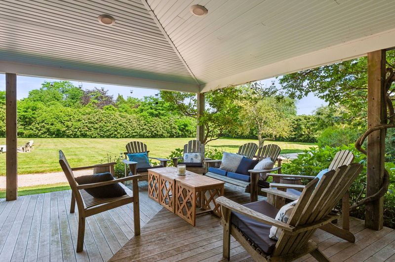 Covered wraparound porch looking over the lawn at 645 North Sea Mecox Road, Southampton — photo 5 of 12