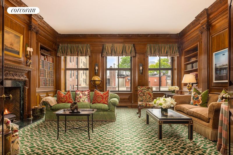 Richly paneled library with wood-burning fireplace at 740 Park Avenue 6/7D, Lenox Hill — photo 2 of 12