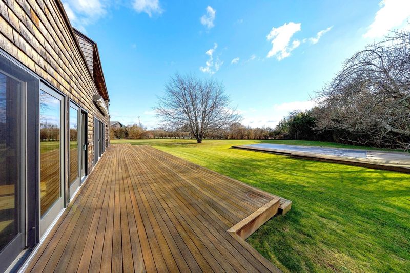 The mahogany deck running the length of the house beside the pool lawn. at 95 Jobs Lane, Bridgehampton — photo 12 of 12
